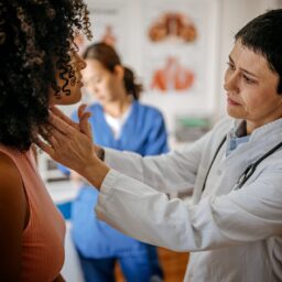 Doctor examining the thyroid of a female patient.
