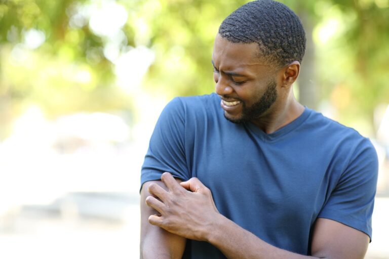 Man scratching arm in park