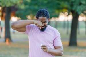 Man with allergies rubs eyes